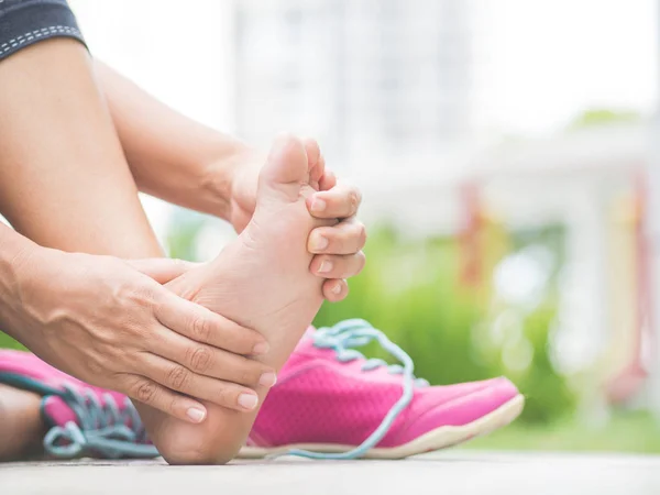 Closeup woman massaging her painful foot while exercising. — Stock Photo, Image