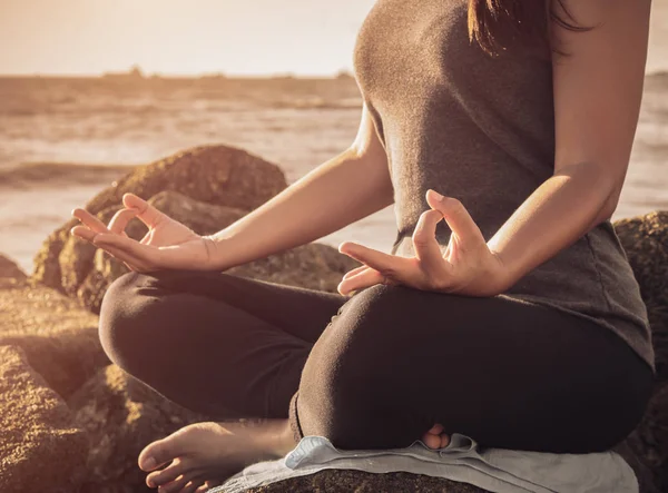 Concepto de yoga. Primeros planos de la mano de la mujer practicando la pose de loto en la playa al atardecer — Foto de Stock