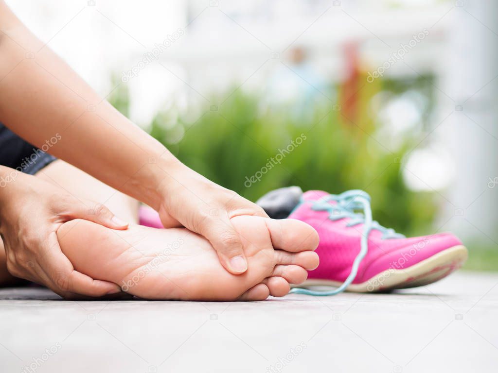 Closeup woman massaging her painful foot while exercising.   