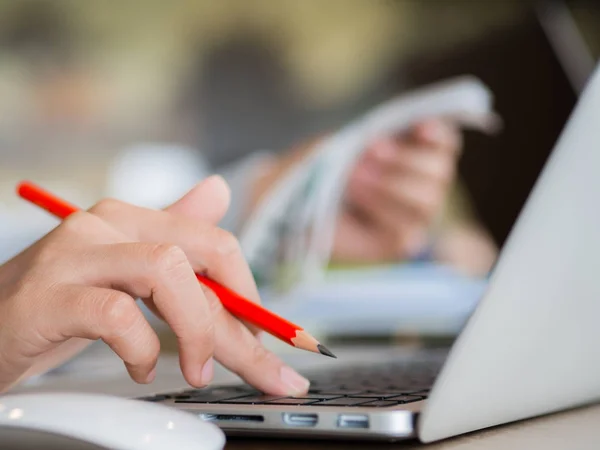 Närbild kvinna hand arbetar på hennes laptop med röd penna. — Stockfoto