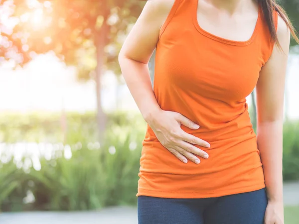 Sport meisje hebben maagpijn na het joggen uitwerkt in park. — Stockfoto