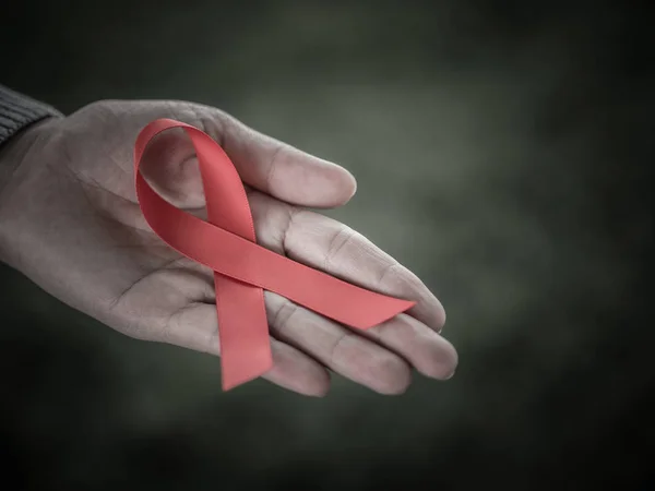 Closeup woman hands holding red ribbon