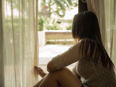 Perdeleri tutan üzgün kadın açmak için dışarı bakmak için 