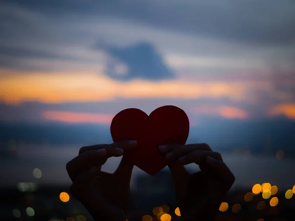 Günbatımı sırasında güzel kalp tutan siluet el. 