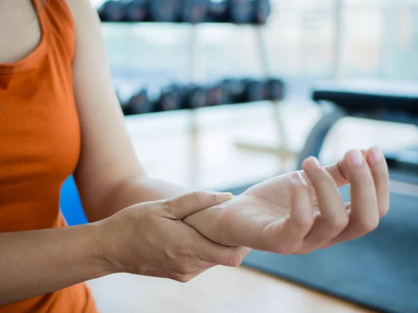 Jonge vrouw masseert haar pols na het sporten — Stockfoto