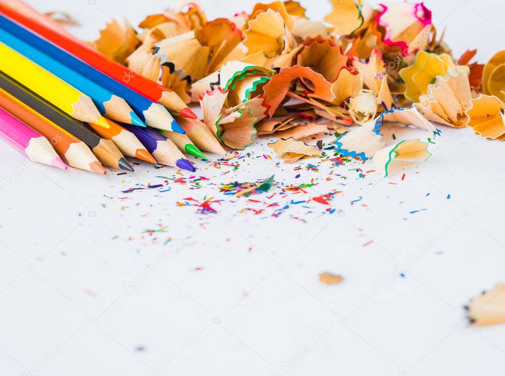 Colorful pencils with colorful pencil shavings on white background