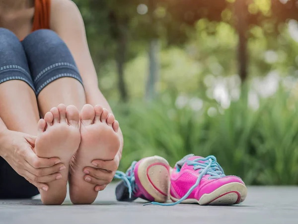 Mujer de primer plano masajeando su doloroso pie mientras hace ejercicio . — Foto de Stock