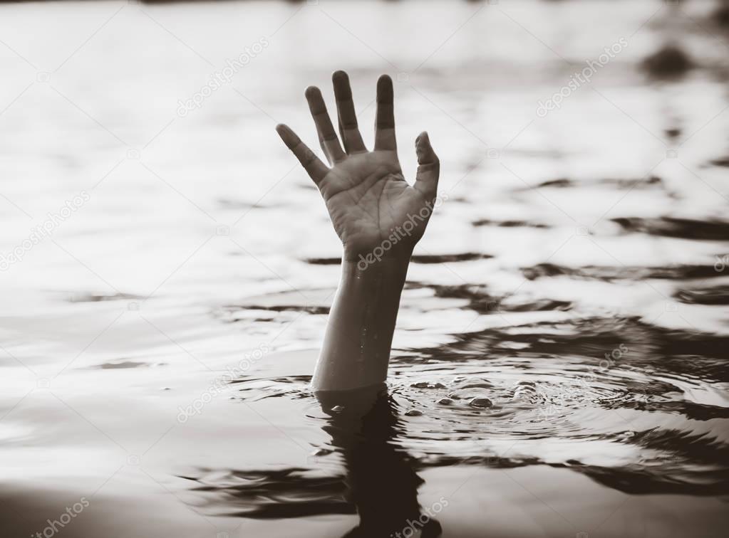 Black and white hand of drowning man needing help. 