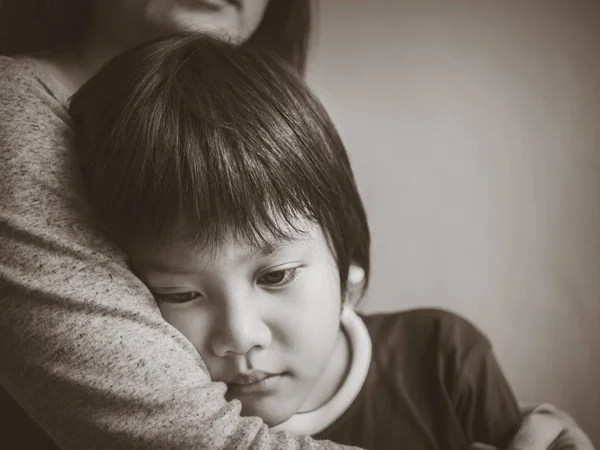 Negro y blanco triste chico siendo abrazado por su madre en casa . — Foto de Stock