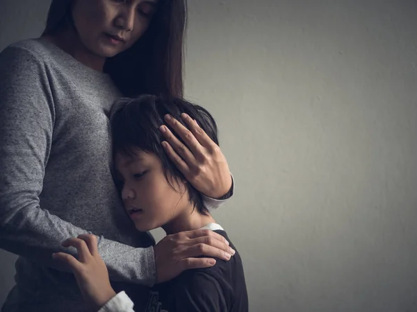 Trauriger kleiner Junge, der zu Hause von seiner Mutter umarmt wird. — Stockfoto