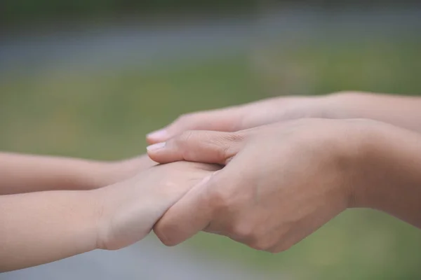 Mother holding a hand of his son with green glass background. — Stock Photo, Image