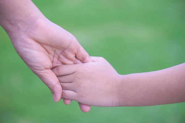 Mãe segurando uma mão de seu filho com fundo de vidro verde . — Fotografia de Stock