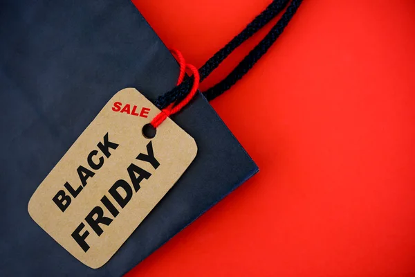 Comprador com saco de papel Black Friday e etiqueta de venda de etiqueta de ingresso no fundo vermelho . — Fotografia de Stock