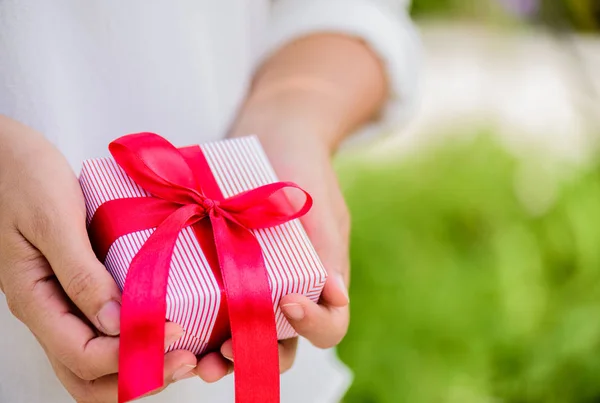 Mano femminile in possesso di una confezione regalo con nastro rosso . — Foto Stock