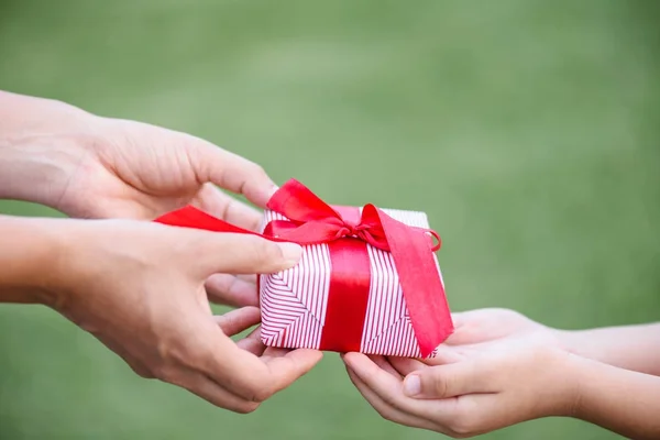 Mother hand giving a gift box to her child.