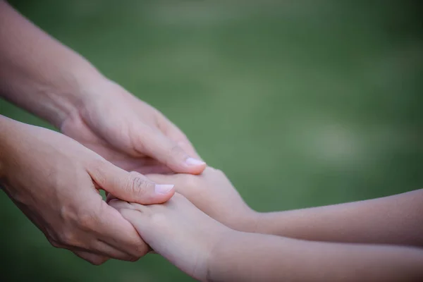 Mother holding a hand of his son with green glass background. Love , famiy and mother day concept. — Stock Photo, Image