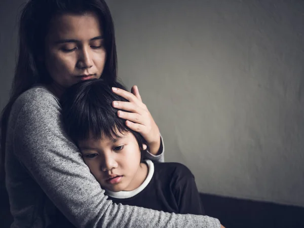 Triste menino sendo abraçado por sua mãe em casa . — Fotografia de Stock