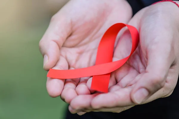 Campaña de sensibilización sobre el sida. Manos femeninas con conciencia roja sobre el sida — Foto de Stock