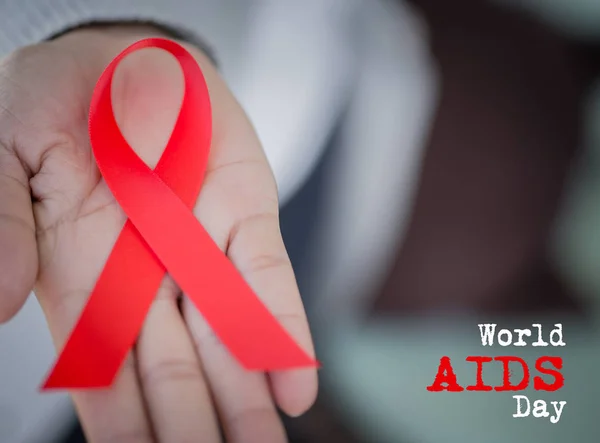 Soft focus woman hand holding red ribbon HIV, world AIDS day