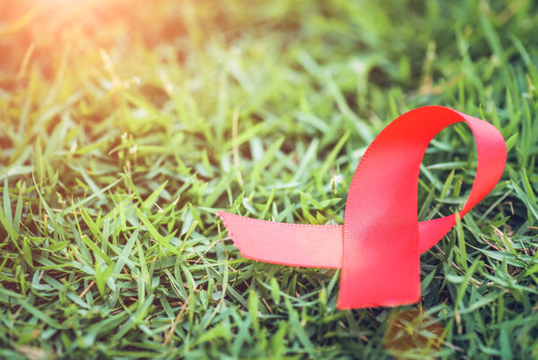 Red ribbon awareness on green grass  background  for World Aids day campaign.