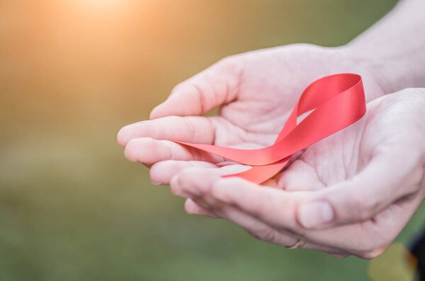 Female hands holding red AIDS awareness ribbon. 