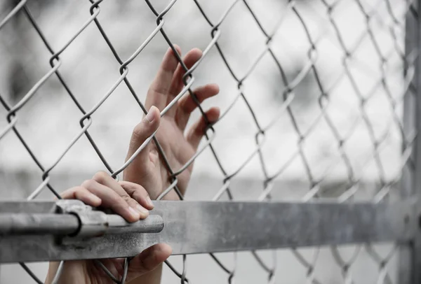 Mano della donna tenuta sulla recinzione di collegamento a catena per ricordare il concetto di Giornata dei Diritti Umani . — Foto Stock