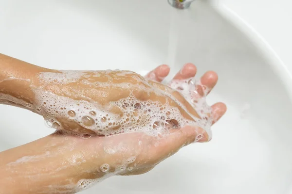 Жінка миє руки з милом під краном з водою у ванній . — стокове фото