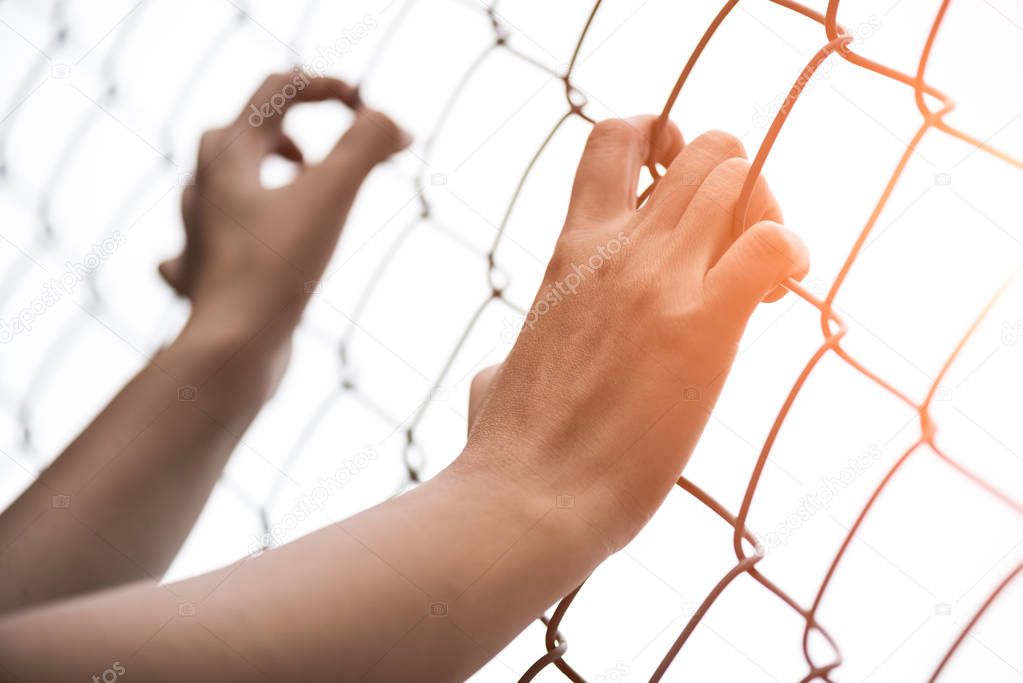 Woman hand holding on chain link fence 