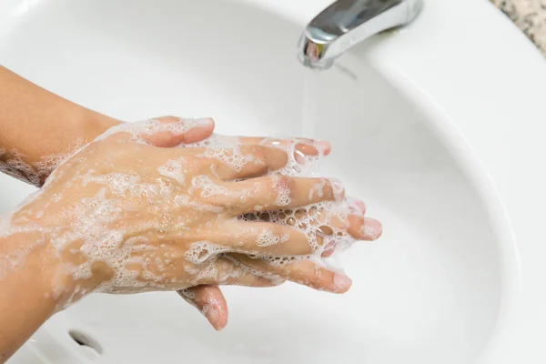 Fokus selektif wanita mencuci tangan dengan sabun di bawah keran dengan air di kamar mandi . — Stok Foto