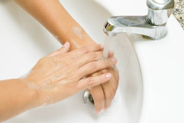 Primeros planos mujer lavándose las manos con jabón debajo del grifo con agua — Foto de Stock