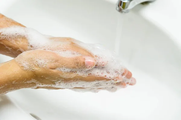 Primeros planos mujer lavándose las manos con jabón debajo del grifo con agua — Foto de Stock