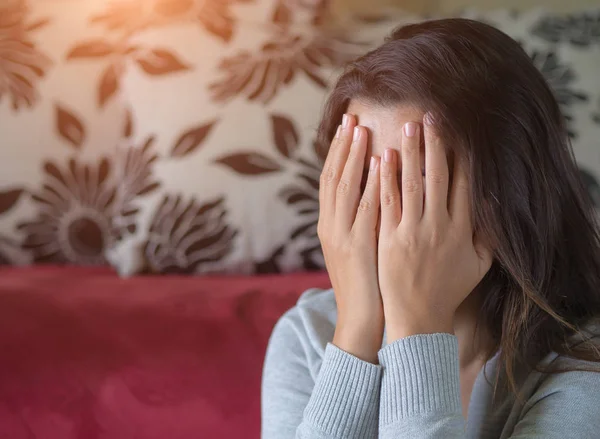 Mujer deprimida sentada junto al sofá en casa . — Foto de Stock