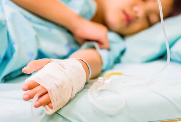 A mão de criança de close-up dorme em uma cama no hospital com solução salina intravenosa . — Fotografia de Stock