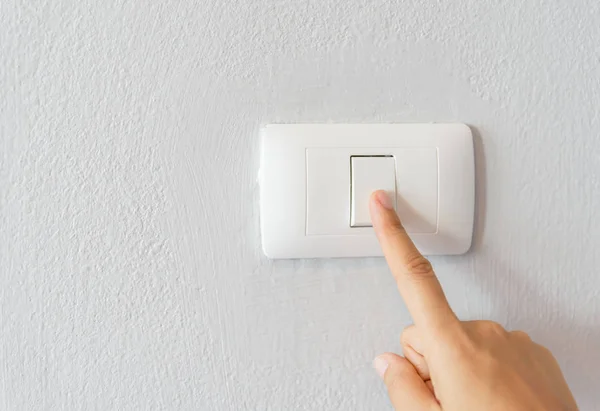 Primer plano del dedo de la mujer que enciende el interruptor de luz — Foto de Stock