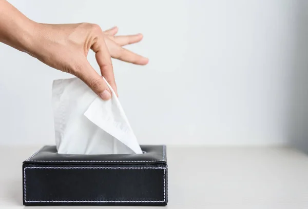 Woman hand picking white tissue paper from tissue box.