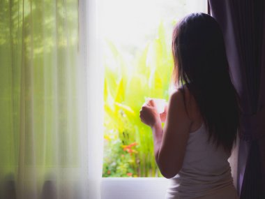 Kahve içme ve dışında seyir açılan pencerede duran genç güzel kadın