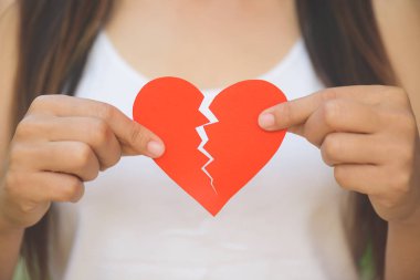 Genç kadın kırmızı gösterilen kağıt kalp sökük. 