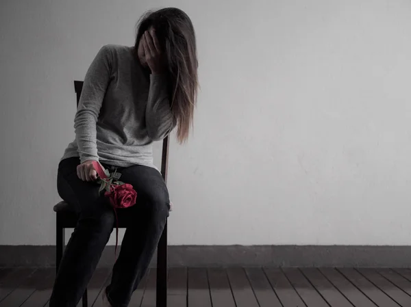 Deprimerad broken hearted kvinna sitter och gråter med röd ros — Stockfoto