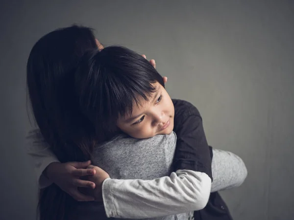Primer plano triste niño siendo abrazado por su madre en casa . — Foto de Stock