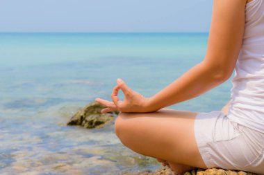 Yoga kavramı. kadın el pratik lotus poz kayaya batımında sahilde oturmuş.