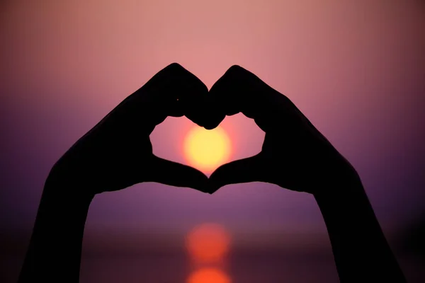 Silhouette der Frau Hände zu Herzform auf Sonnenuntergang Hintergrund — Stockfoto