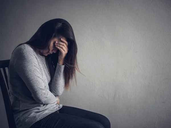 Mujer deprimida sentada en una silla en habitación oscura en casa . —  Fotos de Stock