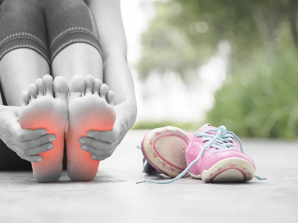 Mujer de primer plano masajeando su doloroso pie mientras hace ejercicio . — Foto de Stock