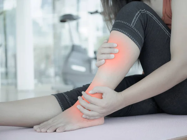 Malheureuse femme assise sur le tapis de yoga avec blessure à la cheville — Photo