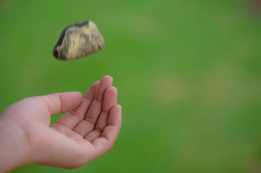 Genç kadın el yeşil arka plan üzerinde taş atma. 