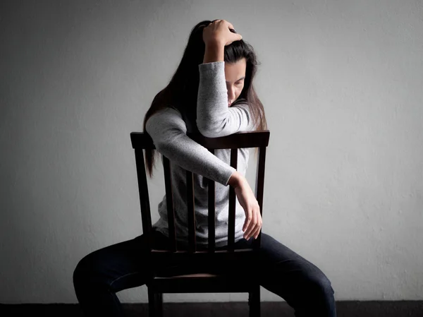 Deprimerad broken hearted kvinna sitter ensam på en trästol — Stockfoto