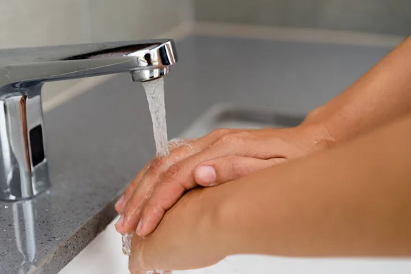Seçici odak kadın banyoda suyla musluk altında sabunla el yıkama. — Stok fotoğraf