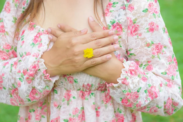 Junge Frau Hand trägt gelbe Blume repräsentieren den Ehering auf grasgrünem Hintergrund — Stockfoto
