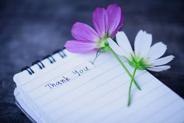 Obrigado texto em um livro de notas de página branca com flor branca romântica em fundo de madeira . — Fotografia de Stock