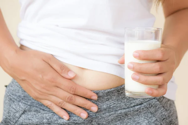 Wanita tangan memegang gelas susu memiliki sakit perut yang buruk karena intoleransi Lactose . — Stok Foto